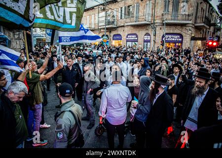 Jérusalem, Israël. 31 mars 2024. Une foule juive ultra orthodoxe se réunit devant les manifestants lors d'une manifestation. Des dizaines de manifestants du mouvement des Frères d'armes ont organisé une manifestation dans le quartier ultra-orthodoxe de Mea Shearim à Jérusalem, appelant à la conscription de la communauté aux FDI, dimanche avait été la date limite pour le gouvernement de proposer une législation pour résoudre le problème, mais Netanyahou a déposé une demande de dernière minute à la Cour suprême pour un moratoire de 30 jours. Crédit : SOPA images Limited/Alamy Live News Banque D'Images