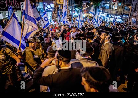 Jérusalem, Israël. 31 mars 2024. Les manifestants défilent avec des drapeaux israéliens dans le quartier ultra orthodoxe de Mea Shearim. Des dizaines de manifestants du mouvement des Frères d'armes ont organisé une manifestation dans le quartier ultra-orthodoxe de Mea Shearim à Jérusalem, appelant à la conscription de la communauté aux FDI, dimanche avait été la date limite pour le gouvernement de proposer une législation pour résoudre le problème, mais Netanyahou a déposé une demande de dernière minute à la Cour suprême pour un moratoire de 30 jours. (Photo par Eyal Warshavsky/SOPA images/SIPA USA) crédit : SIPA USA/Alamy Live News Banque D'Images