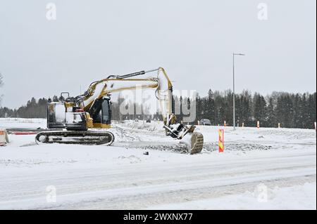 Une excavatrice travaille au milieu d'un paysage enneigé, déblayant la neige ou engagée dans la construction Banque D'Images