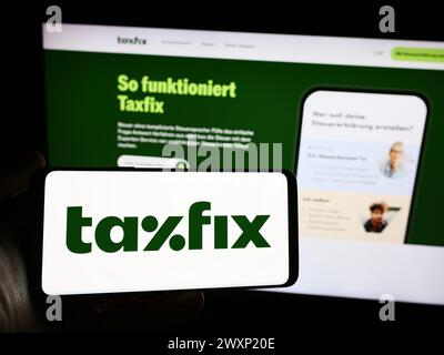 Personne tenant un smartphone avec le logo de la société allemande de logiciels fiscaux Taxfix se en face du site Web. Concentrez-vous sur l'affichage du téléphone. Banque D'Images