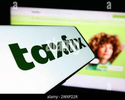 Téléphone portable avec le logo de la société allemande de logiciels fiscaux Taxfix se en face du site Web de l'entreprise. Concentrez-vous sur le centre de l'écran du téléphone. Banque D'Images