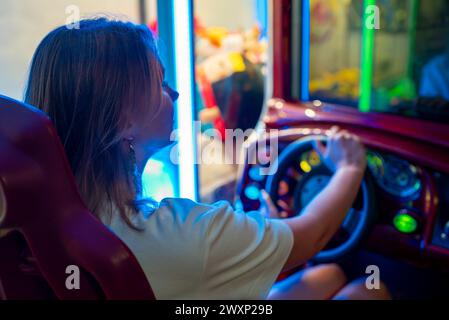 Femme jouant au jeu de simulateur de course dans le parc à thème. Banque D'Images