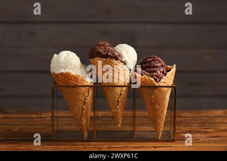 Cuillères à crème glacée savoureuses dans des cônes de gaufre sur une table en bois, gros plan Banque D'Images