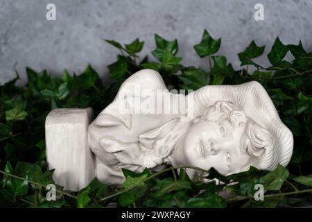 Allemagne stature tête sculptée, tête sculptée dans la pierre blanche, fille avec un chapeau antique.avec des feuilles vertes Banque D'Images