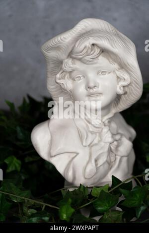 Allemagne stature tête sculptée, tête sculptée dans la pierre blanche, fille avec un chapeau antique.avec des feuilles vertes Banque D'Images