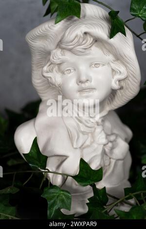 Allemagne stature tête sculptée, tête sculptée dans la pierre blanche, fille avec un chapeau antique.avec des feuilles vertes Banque D'Images