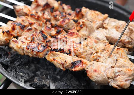Mesure de la température du délicieux kebab sur le brasero en métal, gros plan Banque D'Images