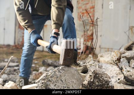 Homme brisant des pierres avec un marteau de forge à l'extérieur, gros plan Banque D'Images