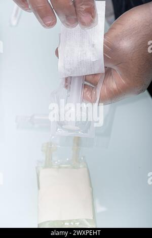 Infirmière avec gant de protection, ouverture de l'emballage de la seringue vertical. Banque D'Images