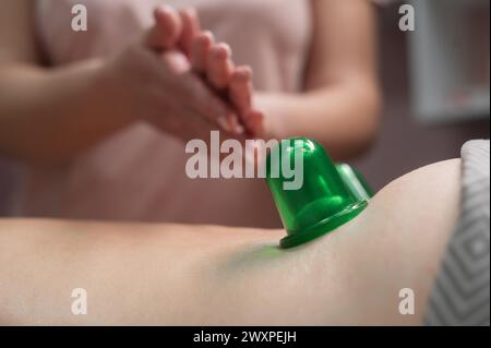Une femme subit une procédure de massage anti-cellulite à l'aide d'un pot à vide. Gros plan du bas du dos. Banque D'Images