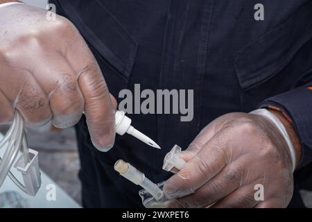 Infirmière avec un gant de protection, connectant l'équipement pour appliquer le médicament au patient. Banque D'Images