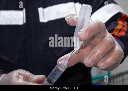 Infirmière avec un gant de protection, enlevant les anti-inflammatoires de l'ampoule en plastique. Banque D'Images