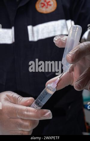 Infirmière avec un gant de protection, enlevant les anti-inflammatoires de l'ampoule en plastique vertical. Banque D'Images