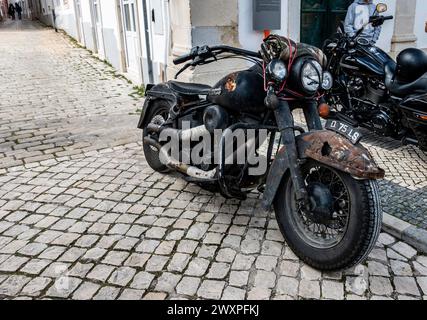 Une moto vintage rouillée avec patine distincte se trouve stationnée sur une vieille rue pavée, à Loule, au Portugal. Banque D'Images