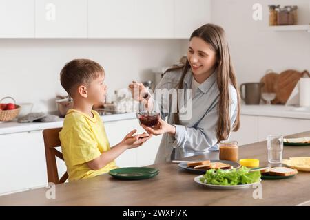 Petit garçon avec sa mère faisant des toasts avec de la confiture dans la cuisine Banque D'Images