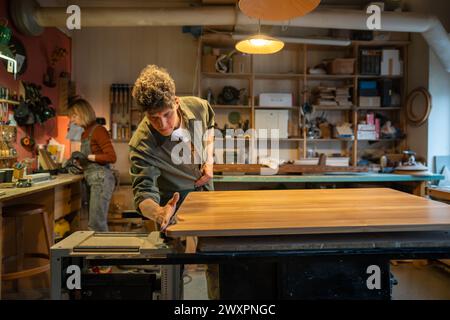 Atelier de menuiserie, artisan pro travaillant. Homme menuisier maître artisan travaille avec la surface de la table Banque D'Images