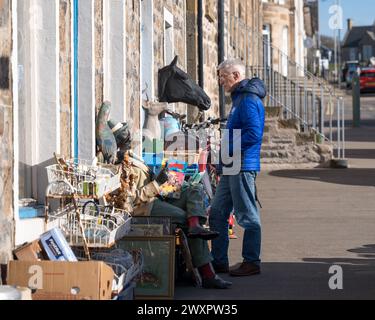 31 mars 2024. Seafield Street, Cullen, Moray, Écosse. C'est un homme debout devant une exposition de trottoir d'antiquités et de objets de collection. Banque D'Images