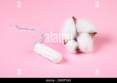 Tampon hygiénique et fleur de coton sur fond rose. Produit D'HYGIENE menstruelle FEMININE. Concept de santé pour les femmes. Banque D'Images