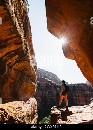 Secret Subway Cave Boynton Canyon Sedona randonneuse solo regardant dans le canyon avec étoile de soleil. Banque D'Images