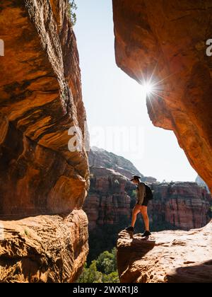 Secret Subway Cave Boynton Canyon Sedona Backpacker solo regardant dans la falaise avec Sunstar. Banque D'Images