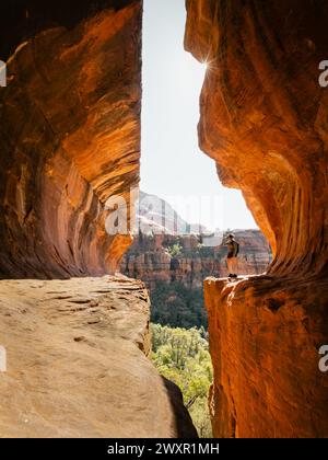 Secret Subway Cave Boynton Canyon Sedona randonneur solo femme debout à côté de la falaise avec étoile de soleil. Banque D'Images