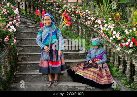 Fleurs des femmes hmong assises sur les escaliers du palais des rois Hmong (Vau Meo) à bac Ha, province de Lao Cai, Vietnam Banque D'Images