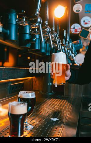 Bière légère artisanale, lager, froide et mousseuse versée dans le verre à pied par le barman au bar traditionnel. Servir de la bière artisanale du robinet. Concept d'Oktoberfest Banque D'Images