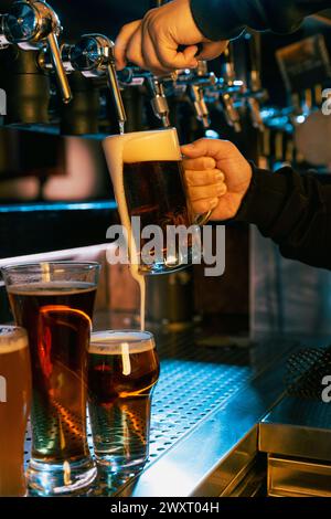 Gamme de différents types de bière avec une nouvelle addition versée par le barman. Servir de la bière artisanale du robinet. Banque D'Images