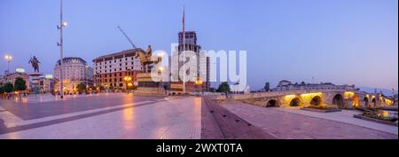 Skopje, Macédoine du Nord - 05 octobre 2023 : vue panoramique au lever du soleil sur la place de Macédoine et le Pont de pierre, avec divers monuments, habitants, et v Banque D'Images