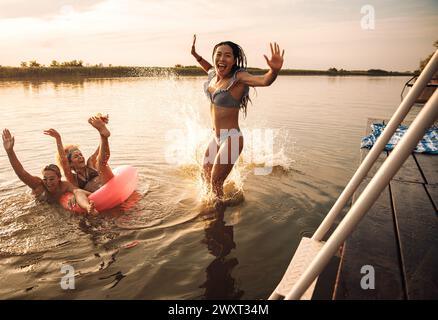 Groupe d'amies profitant d'une journée d'été sautant au lac. Banque D'Images