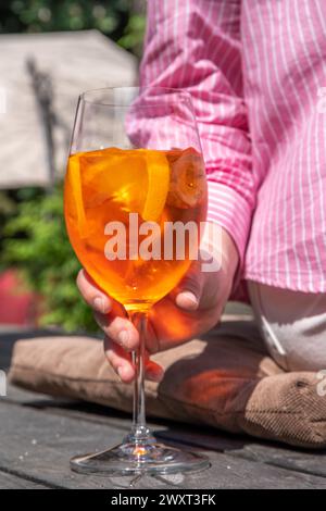 Une fille boit de l'alcool glacé cocktail Aperol spritz sur la terrasse d'été, dans un café ou un restaurant Banque D'Images