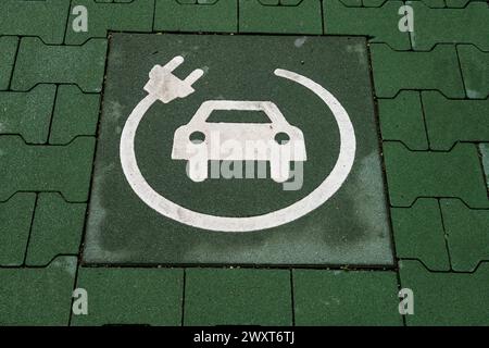 voiture électrique, la station de charge est indiquée par le symbole de voiture et le câble de charge. par espace est réservé à la charge électrique, symbole sur le plancher Banque D'Images