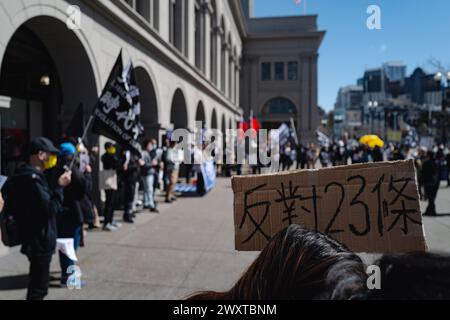 Un jeune militant tient une pancarte en l'air, exhortant la communauté internationale à se tenir aux côtés de Hong Kong contre les lois oppressives de sécurité nationale de l'article 23. Dans une puissante démonstration de solidarité, les manifestants de San Francisco se sont rassemblés pour se rassembler contre la mise en œuvre de l'article 23 des lois sur la sécurité nationale à Hong Kong. La manifestation, qui s’est déroulée au cœur de la ville, a attiré une foule diversifiée d’activistes, d’étudiants et de citoyens concernés. Banque D'Images