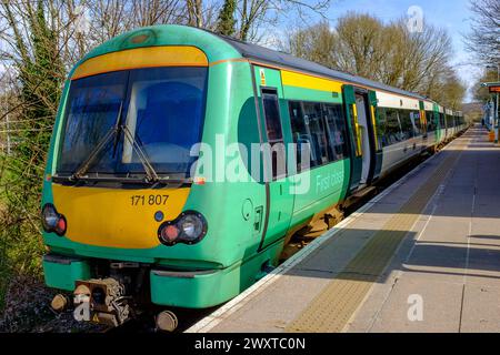 Un train Southern Railway en couleurs verte et jaune se dresse avec ses portes ouvertes sur un quai de gare vide Banque D'Images