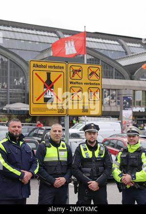 Hambourg, Allemagne. 02 avril 2024. Des agents de la police fédérale et de l'État ainsi que des employés des services de sécurité de Hochbahnwache et DB, la « Quadro-Streife » (patrouille de quatre hommes), se tiennent devant un nouveau panneau interdisant la consommation d'alcool à côté d'un panneau interdisant les armes devant la gare principale. Depuis mardi 02.04.2024, la consommation d'alcool est interdite dans la zone de la gare centrale de Hambourg. Crédit : Christian Charisius/dpa/Alamy Live News Banque D'Images