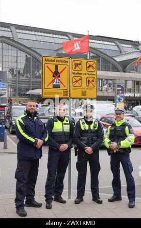 Hambourg, Allemagne. 02 avril 2024. Des agents de la police fédérale et de l'État ainsi que des employés des services de sécurité de Hochbahnwache et DB, la « Quadro-Streife » (patrouille de quatre hommes), se tiennent devant un nouveau panneau interdisant la consommation d'alcool à côté d'un panneau interdisant les armes devant la gare principale. Depuis mardi 02.04.2024, la consommation d'alcool est interdite dans la zone de la gare centrale de Hambourg. Crédit : Christian Charisius/dpa/Alamy Live News Banque D'Images