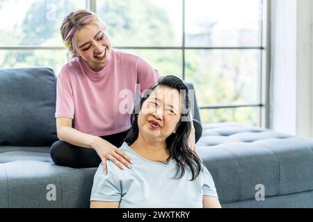 La fille donnant massage à sa mère tout en étant assise sur le canapé Banque D'Images