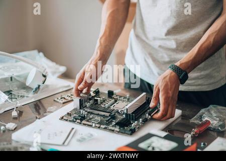 Bricoleur de technologie : au milieu d'un éventail de pièces électroniques, un artisan s'engage dans la tâche délicate de la maintenance informatique Banque D'Images