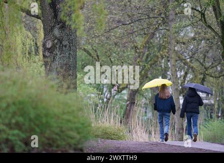 Hambourg, Allemagne. 02 avril 2024. Deux jeunes femmes vont se promener dans un parc sous la pluie. Crédit : Marcus Brandt/dpa/Alamy Live News Banque D'Images