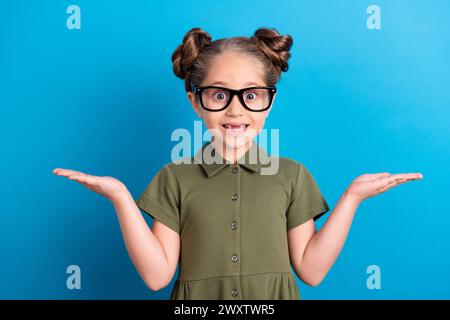 Photo d'écolier doux démontrer deux objets publicité vente porter t shirt isolé bleu brillant fond de couleur Banque D'Images