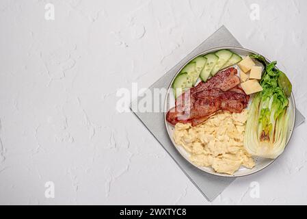 Photographie de nourriture vierge du petit déjeuner avec oeuf brouillé ; bacon frit, concombre, bok choi ; fromage parmesan, régime céto ; brunch ; fond Banque D'Images