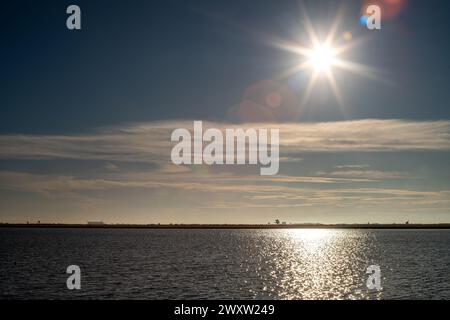 La lumière du soleil se reflète sur l'eau dans les rizières inondées d'Isla Mayor, Séville, avec un ciel clair. Banque D'Images