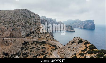 Voiture blanche solitaire sur la route de montagne asphaltée courbe serpentine près du phare de Cap de Formentor côte rocheuse. Île de Majorque, Îles Baléares, Espagne. Banque D'Images