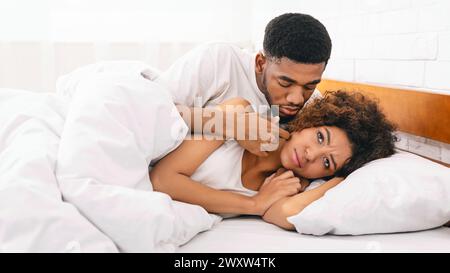 Femme malheureuse au lit, son petit ami s'excuser Banque D'Images