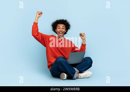 Homme excité avec ordinateur portable célébrant Banque D'Images