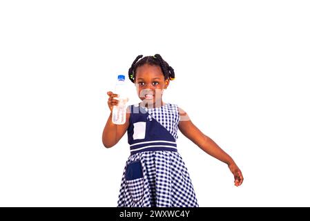 mignonne petite fille vêtue de vêtements d'école tenant la bouteille d'eau en plastique souriant. Banque D'Images