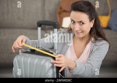 préparation avant de voyager jeune femme mesurant valise Banque D'Images