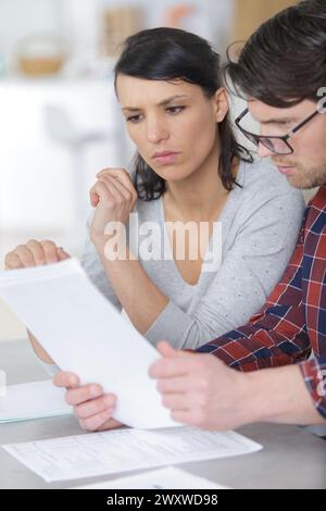 couple sérieux regardant la paperasse ensemble Banque D'Images