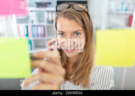 joyeux designer collant des notes sur la fenêtre au bureau Banque D'Images