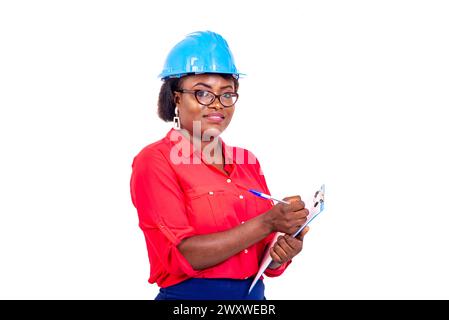 portrait d'une belle femme ingénieur portant un casque de sécurité bleu et écrivant au presse-papiers. Banque D'Images